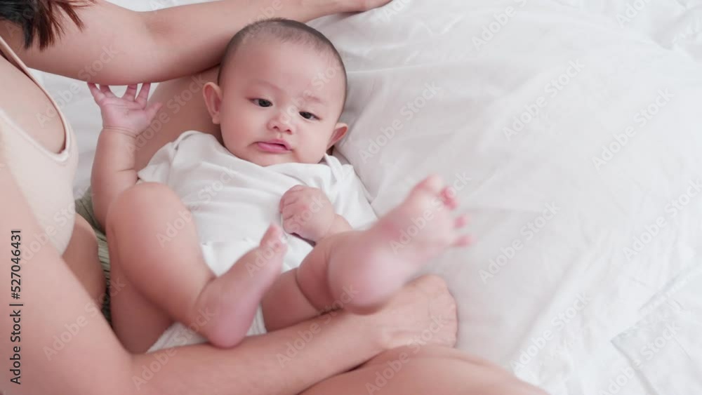 Cute Asian newborn baby boy lying play on white bed with smile happy face. While your mother takes care nearby. Little innocent new infant adorable child in first day of life. Mother's Day concept. Cute Asian newborn baby boy lying play on white bed with smile happy face. While your mother takes care nearby. Little innocent new infant adorable child in first day of life. Mother's Day concept.