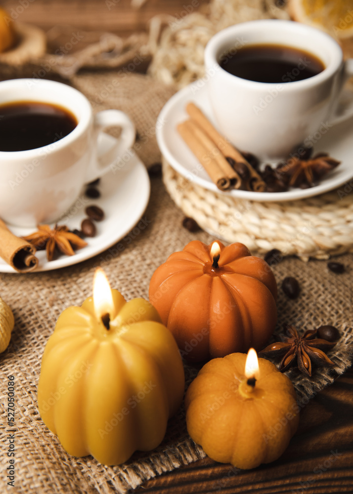 Candles in the form of pumpkins with fragrant coffee on a background of spicy spices of star anise and cinnamon on a brown wooden background.Cozy home decor.Halloween concept.Happy Thanksgiving. Candles in the form of pumpkins with fragrant coffee on a background of spicy spices of star anise and cinnamon on a brown wooden background.Cozy home decor.Halloween concept.Happy Thanksgiving.