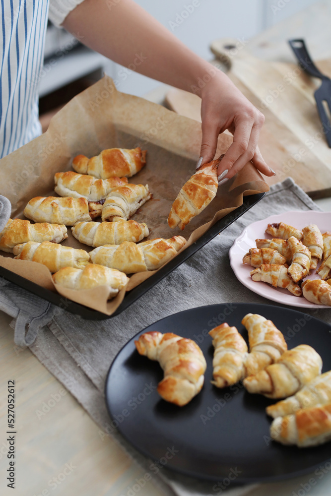 Get a glimpse of the baking process with a brown-haired woman as she effortlessly prepares and photographs her freshly baked croissants in the cozy kitchen.