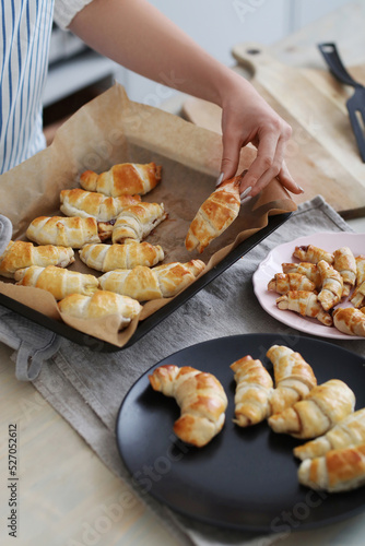 Get a glimpse of the baking process with a brown-haired woman as she effortlessly prepares and photographs her freshly baked croissants in the cozy kitchen.
