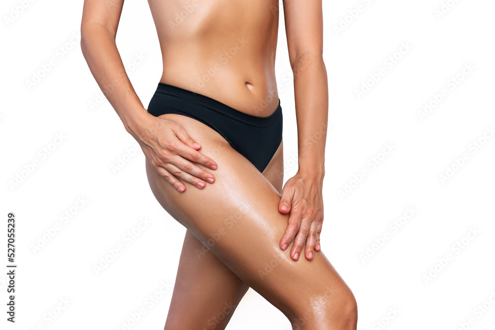 Cropped shot of young fit tanned woman smearing her thigh with cosmetic oil isolated on a white background. Cosmetology, massage, spa products. Skin care. Taking care of the body Cropped shot of young fit tanned woman smearing her thigh with cosmetic oil isolated on a white background. Cosmetology, massage, spa products. Skin care. Taking care of the body