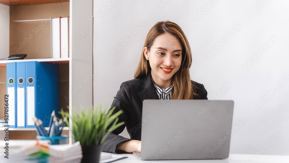 Young Asian female manager using portable computer device while sitting at modern office, work process concept Young Asian female manager using portable computer device while sitting at modern office, work process concept