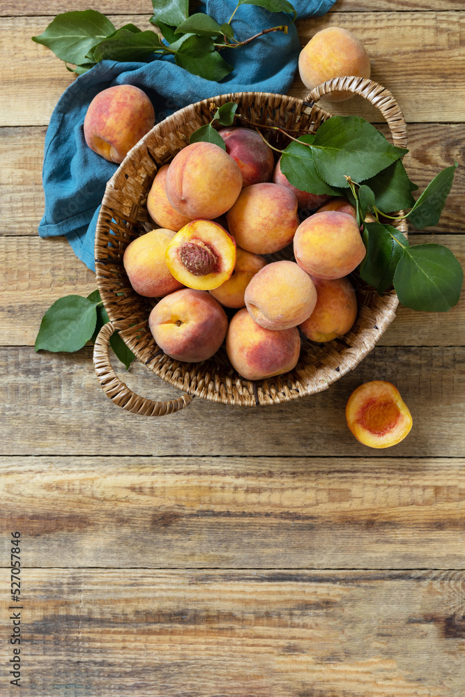 Organic fruits. Fall harvest background. Farmer's market. Basket of ripe peaches on a rustic wooden table. View from above. Copy space.
