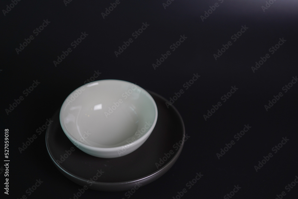 white bowl and black plate on black background white bowl and black plate on black background