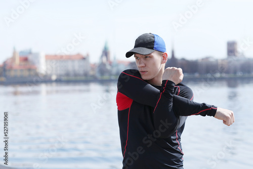 Sporty young man doing exercises near river 