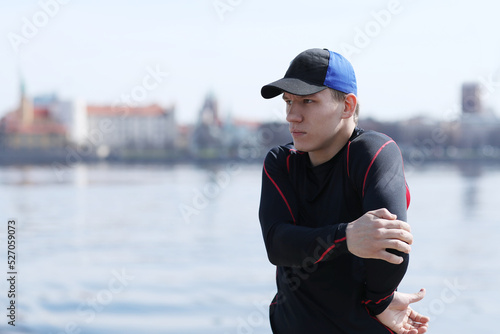 Sporty young man doing exercises near river 