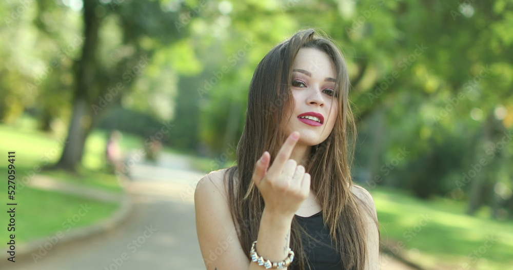 Pretty girl waving hello and inviting to come with hand and finger outdoors Pretty girl waving hello and inviting to come with hand and finger outdoors
