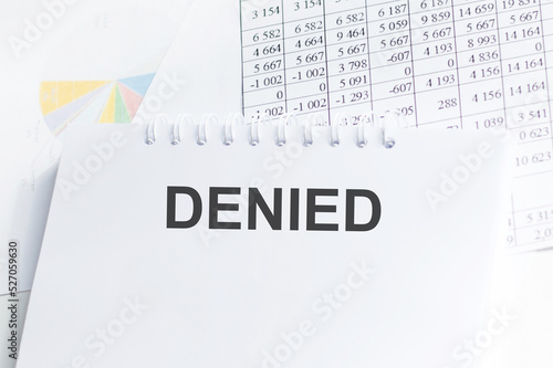 DENIED text on notepad on the table on the background of reports