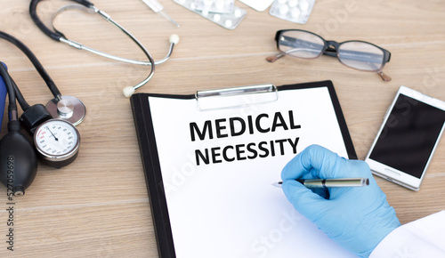 Medical necessity text is written by the hand of a jerk on a white sheet of paper on a table