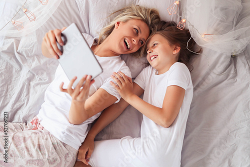 a woman and a little girl laying on a bed, having fun, film, elegant shot, photo of a beautiful, unique design, using a magical tablet