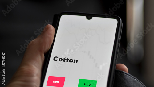 An investor's analyzing the cotton etf fund on screen. A phone shows the ETF's prices cotton to invest, texte en français.
