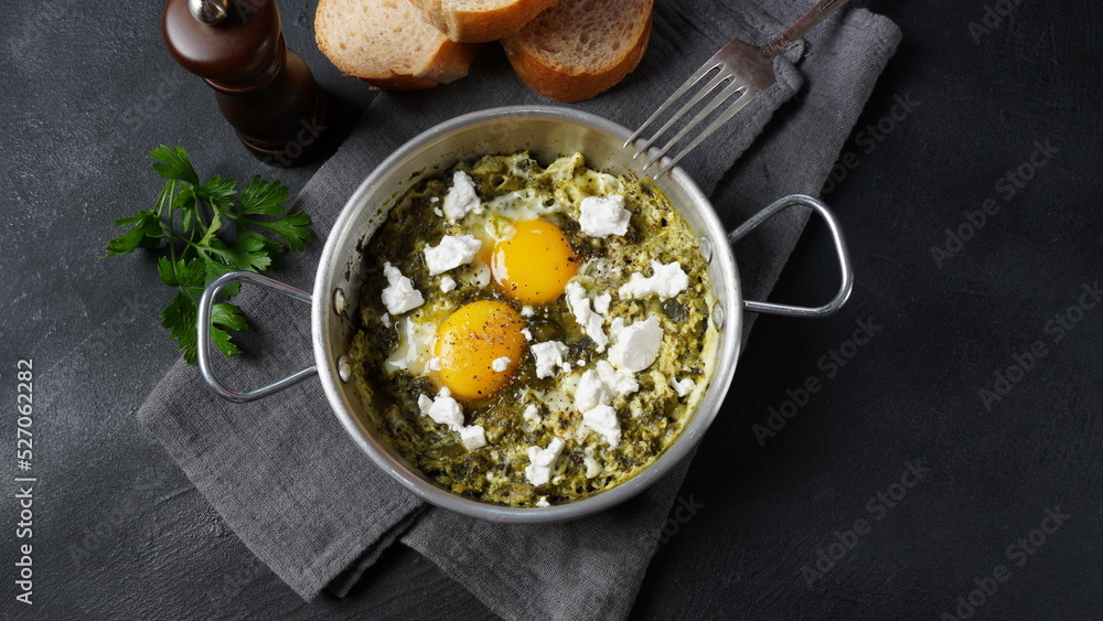 Green shakshuka with spinach, and feta in a frying pan on a table with bread Green shakshuka with spinach, and feta in a frying pan on a table with bread