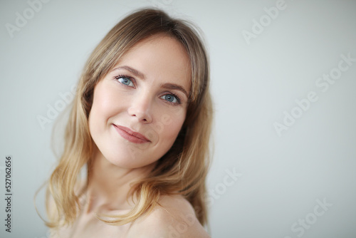 Close view of young blond woman looks at camera and pose at home