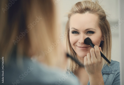 Fototapeta Naklejka Na Ścianę i Meble -  Blonde beautiful woman doing makeup in front of mirror