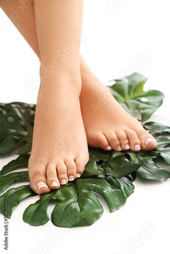 Smooth bare legs women with pedicure on leaves