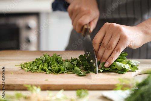 Women’s hands cut greens for salad in the kitchen 