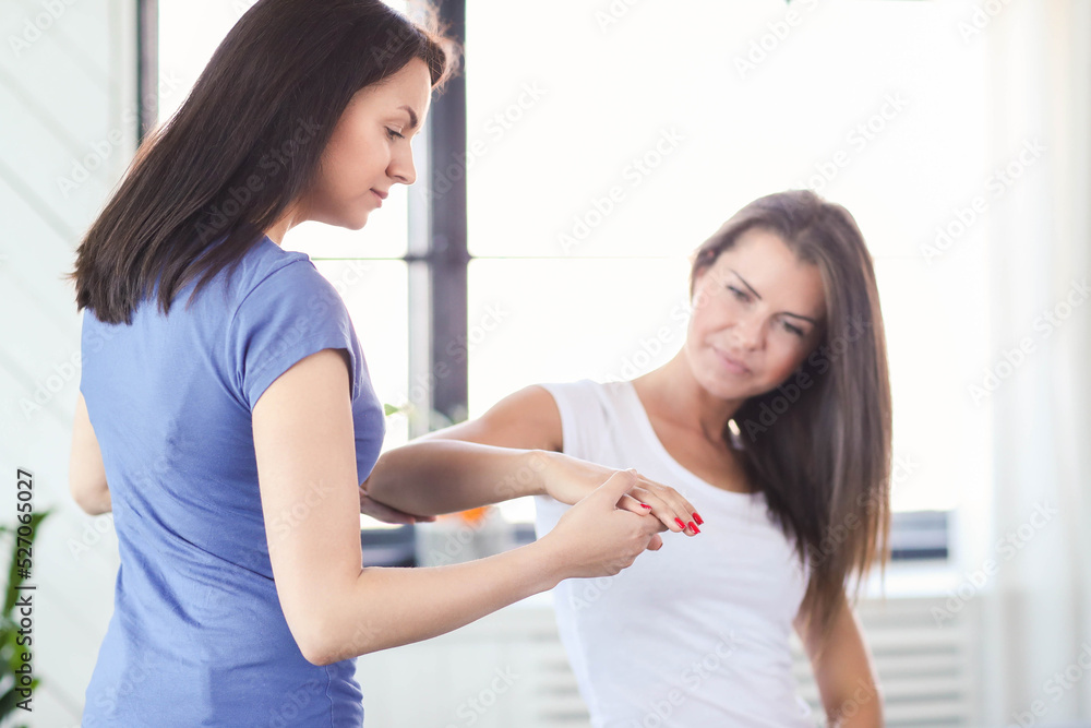 Professional stretches the arm of a young woman at home Professional stretches the arm of a young woman at home