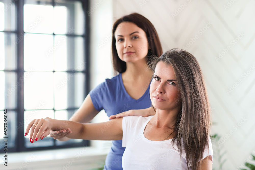 Fototapeta premium Professional stretches the arms of a young woman at home