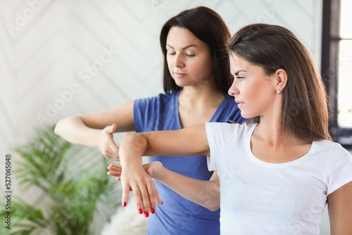 Professional stretches the arms of a young woman at home © racool_studio