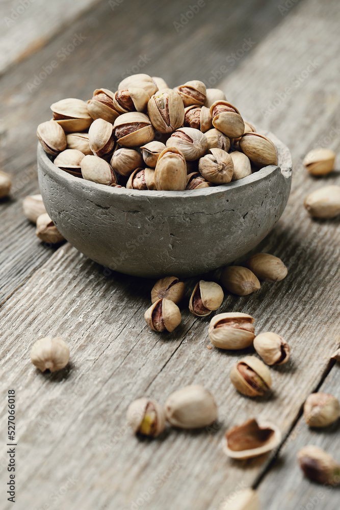 Image of pistachio nuts in bowl isolated on a wooden background. Image of pistachio nuts in bowl isolated on a wooden background.