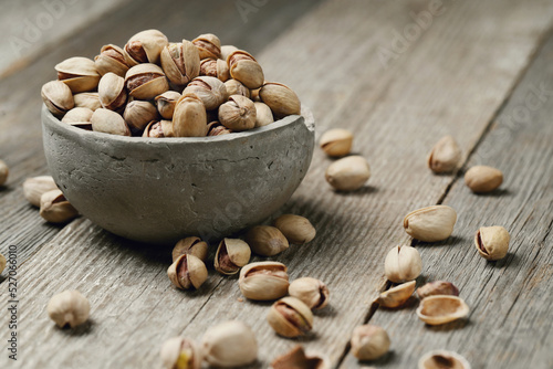 Image of pistachio nuts in bowl isolated on a wooden background.