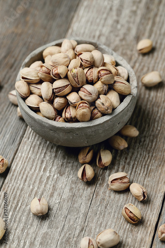 Image of pistachio nuts in bowl isolated on a wooden background.