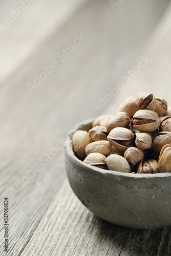 Close view of pistachio nuts in bowl isolated on a wooden background.