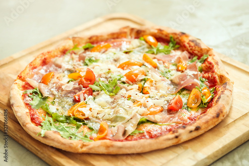 Picture of delicious hot whole pizza with vegetables on a wooden board