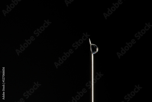 Vaccine drop on syringe needle. Needle with a drop of vaccine on a black background
