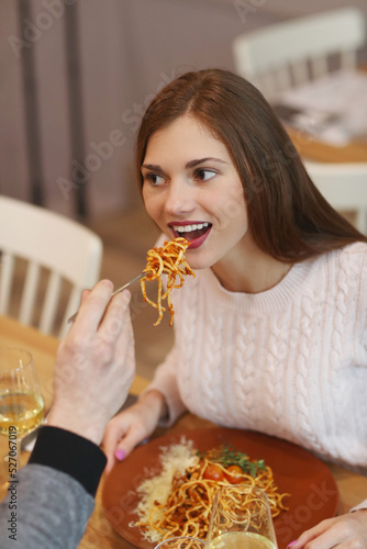 A young man feeds his lover spaghetti at a romantic dinner at a restaurant