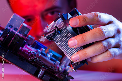 A man's hand inserts a cooler into the motherboard socket