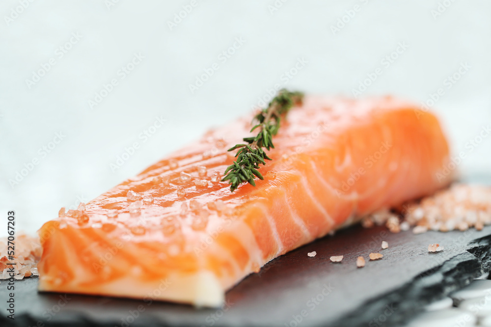 Fresh juicy raw salmon with rosemary and sea salt on a black cutting board Fresh juicy raw salmon with rosemary and sea salt on a black cutting board