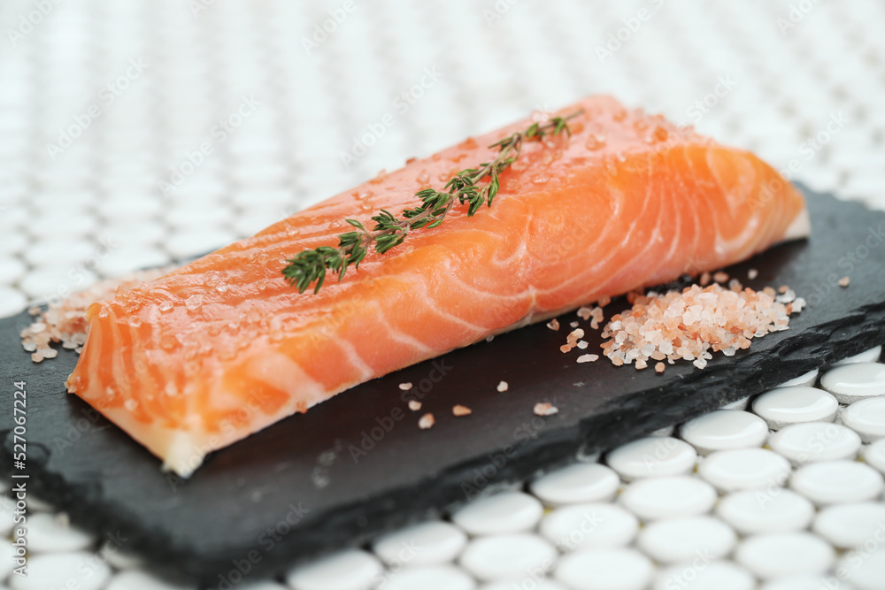 Fresh juicy raw salmon with rosemary and sea salt on a black cutting board Fresh juicy raw salmon with rosemary and sea salt on a black cutting board
