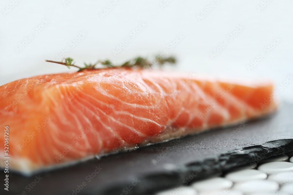 Side view of fresh juicy raw salmon with rosemary on a black cutting board