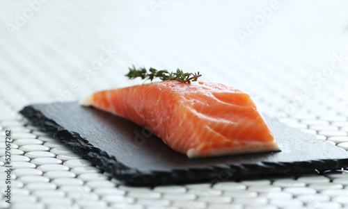 Image of fresh juicy raw salmon with rosemary on a black cutting board