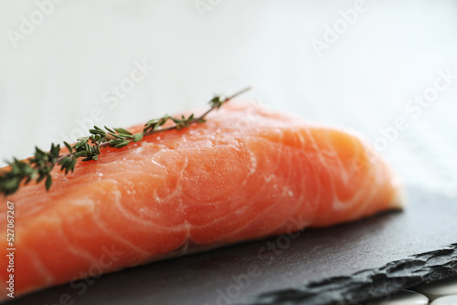 Close view of fresh juicy raw salmon with rosemary on a black cutting board
