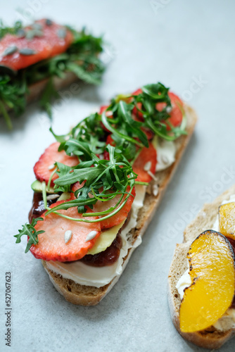 Close view of delicious sweet Bruschetta (sandwiches) with cottage cheese and slices of strawberry on a white background