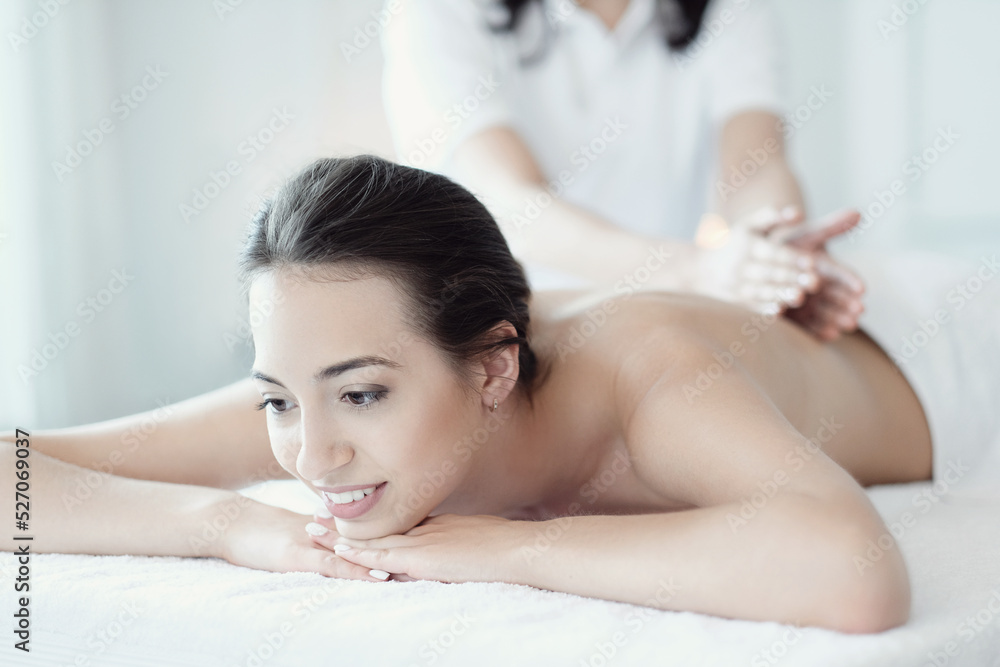 A beautiful young woman enjoying a back massage in the spa salon A beautiful young woman enjoying a back massage in the spa salon