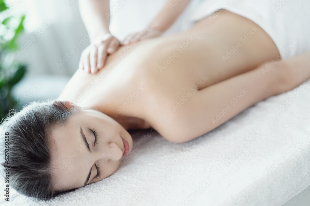A beautiful young woman enjoying a back massage in the spa salon A beautiful young woman enjoying a back massage in the spa salon