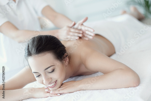 A beautiful young woman enjoying a back massage in the spa salon