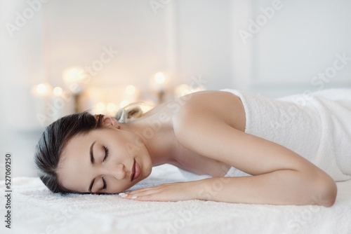 Relaxed beautiful young woman lying on the couch after massage in the spa salon