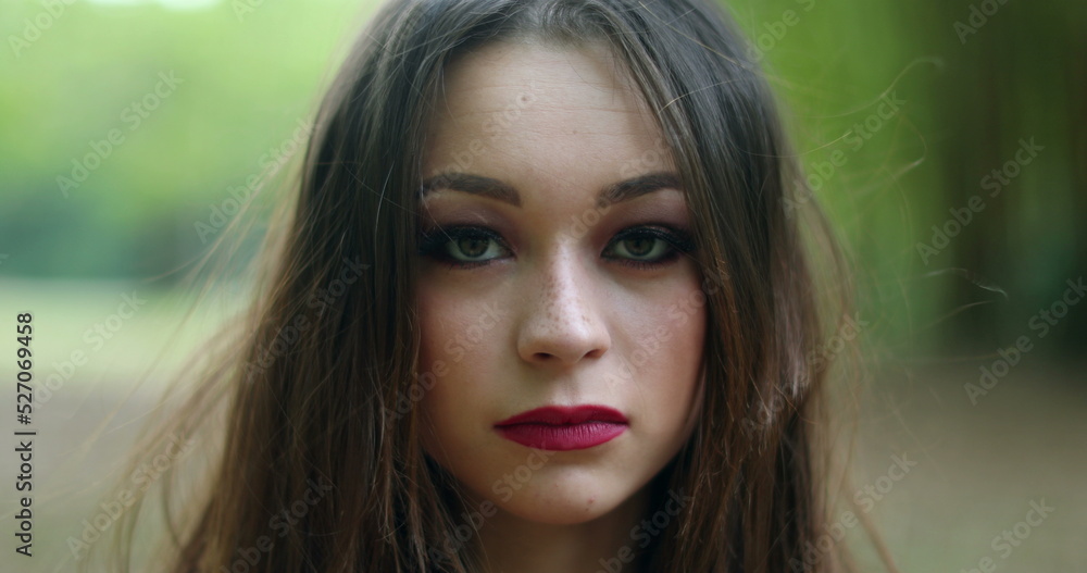 Portrait of serious young woman in 20s looking to camera in outdoors Portrait of serious young woman in 20s looking to camera in outdoors