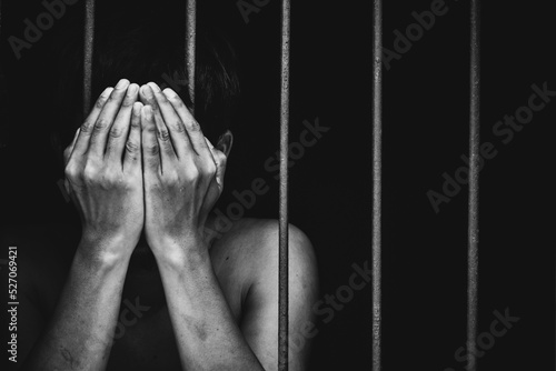 prison man crime in gaol use both hands to cover face on black background.concept for prisoner,sadness,detain,erroneousness photo