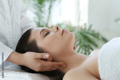 Beautician doing neck massage of young beautiful relaxed woman in spa salon