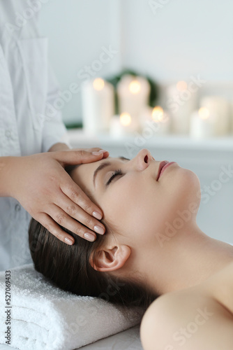 Beautician doing massage of young beautiful relaxed woman in spa salon