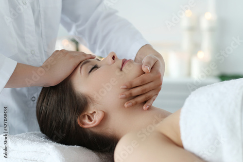 Beautician doing neck massage of young beautiful relaxed woman in spa salon