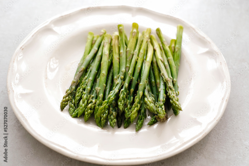 Fresh tasty asparagus in a plate on a white background Fresh tasty asparagus in a plate on a white background