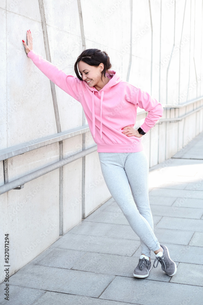 Young beautiful girl in pink sportswear with hood posing outdoor