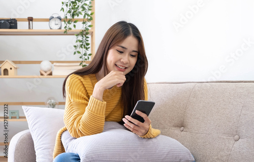 Free time. Asian girl checking social networks on phone, resting on sofa, panorama with free space