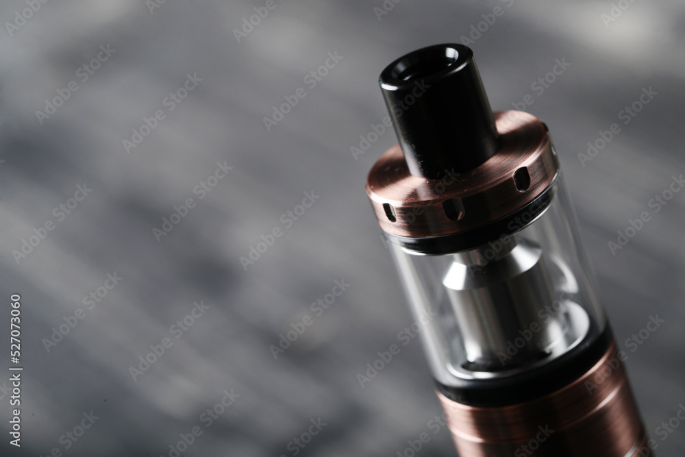 An electronic cigarette for smoking nicotine on a dark wooden background An electronic cigarette for smoking nicotine on a dark wooden background